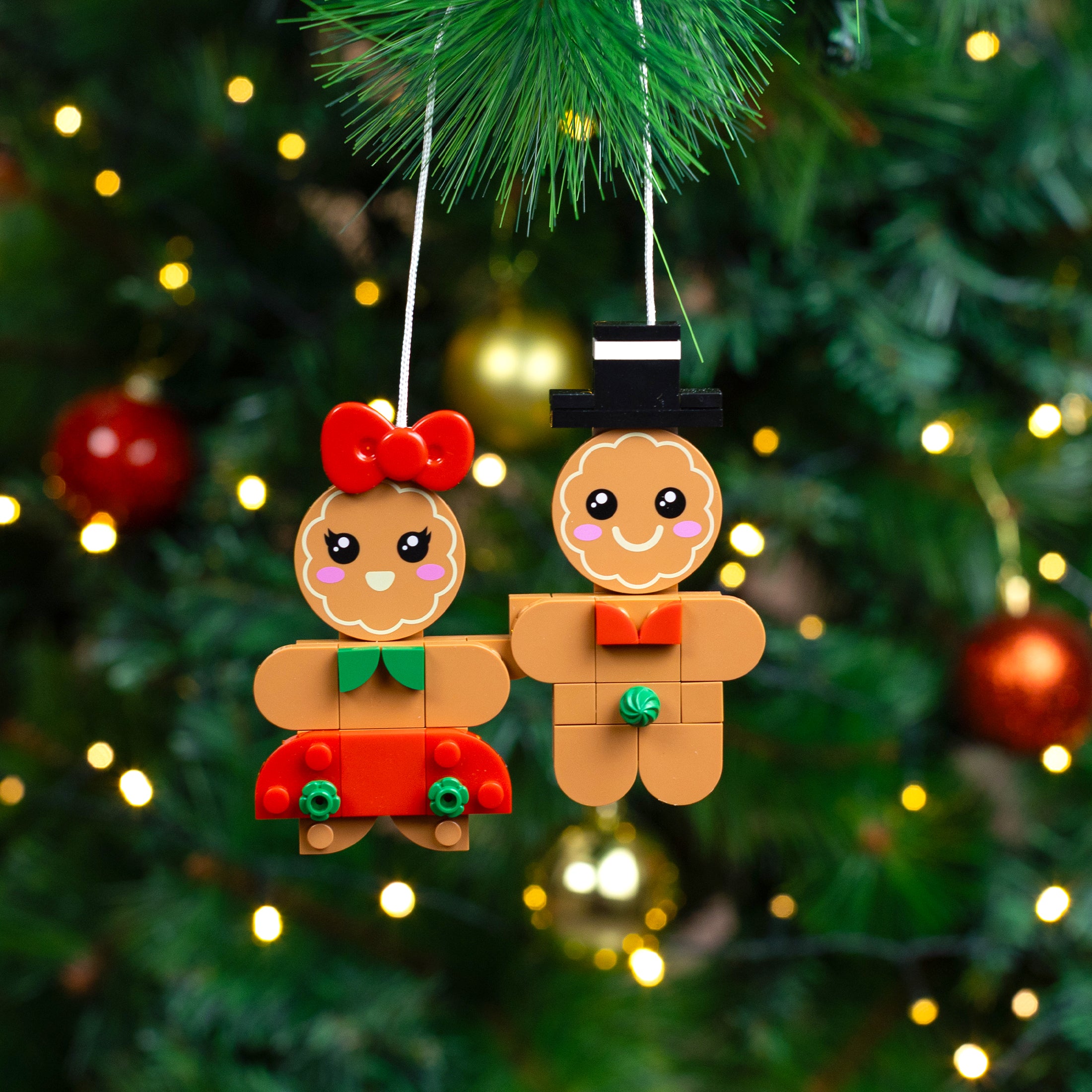 Two gingerbread-themed Christmas ornaments hanging on a decorated tree.