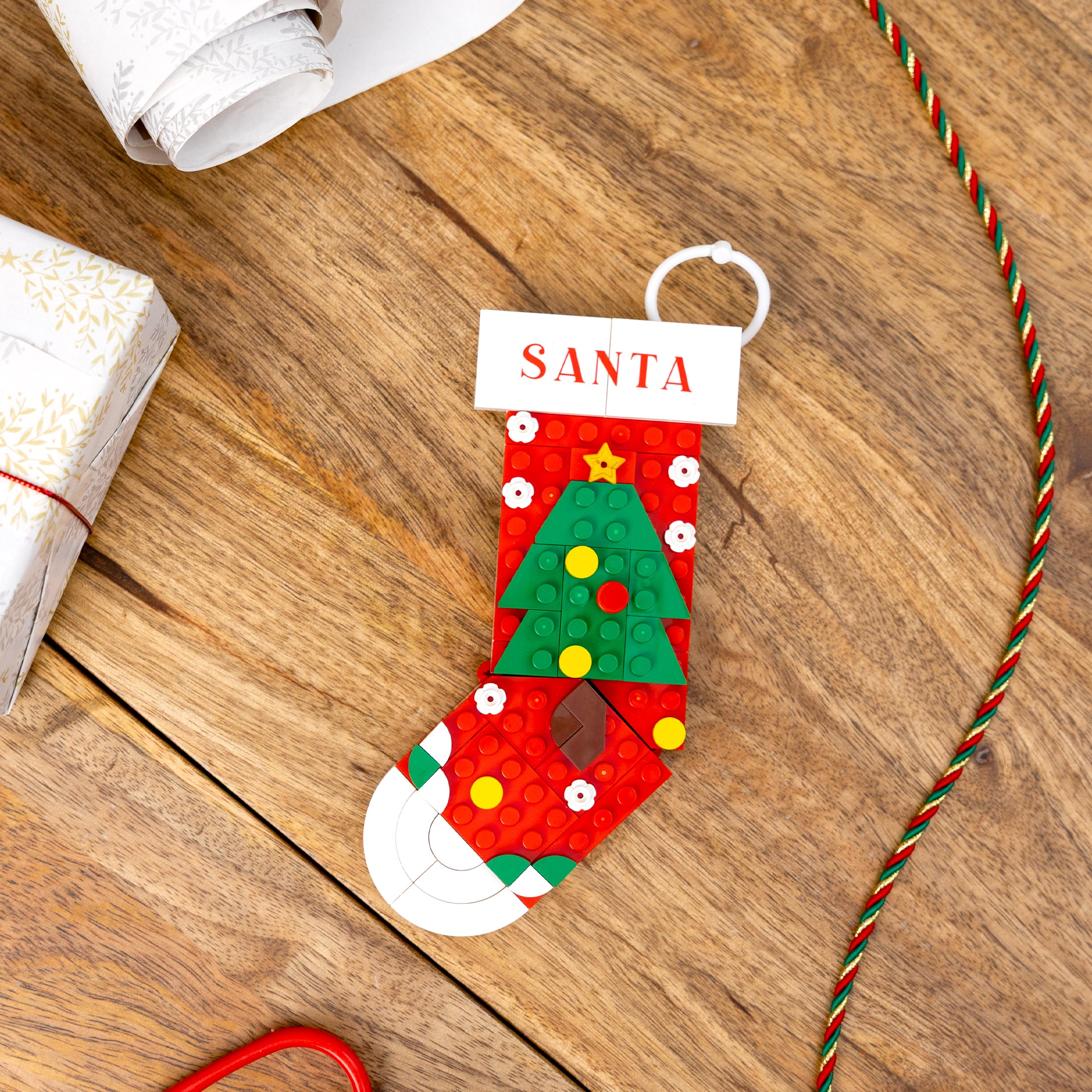 Christmas-themed stocking with a tree design and 'Santa' label on a wooden surface.