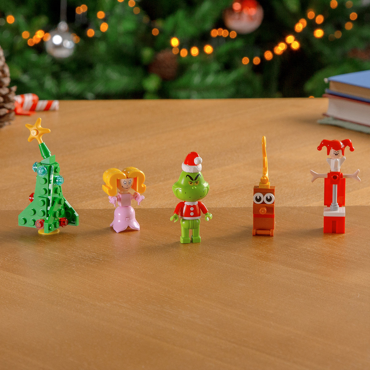 Set of Christmas-themed figurines on a wooden surface with a blurred festive background.