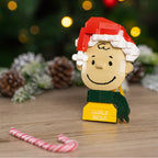 Toy figure of Charlie Brown wearing a Santa hat with Christmas decorations in the background.