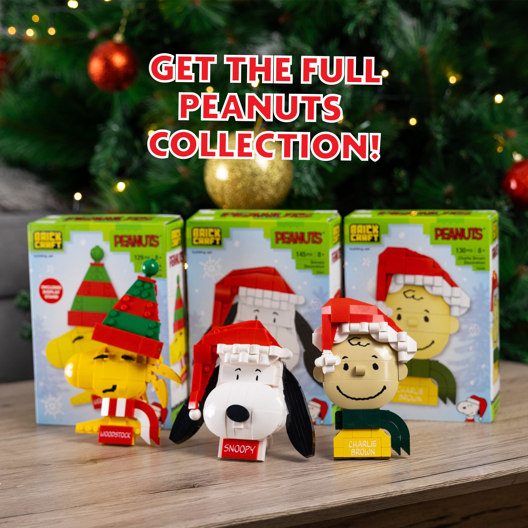 Peanuts-themed figurines with packaging on a wooden surface with a Christmas tree in the background.