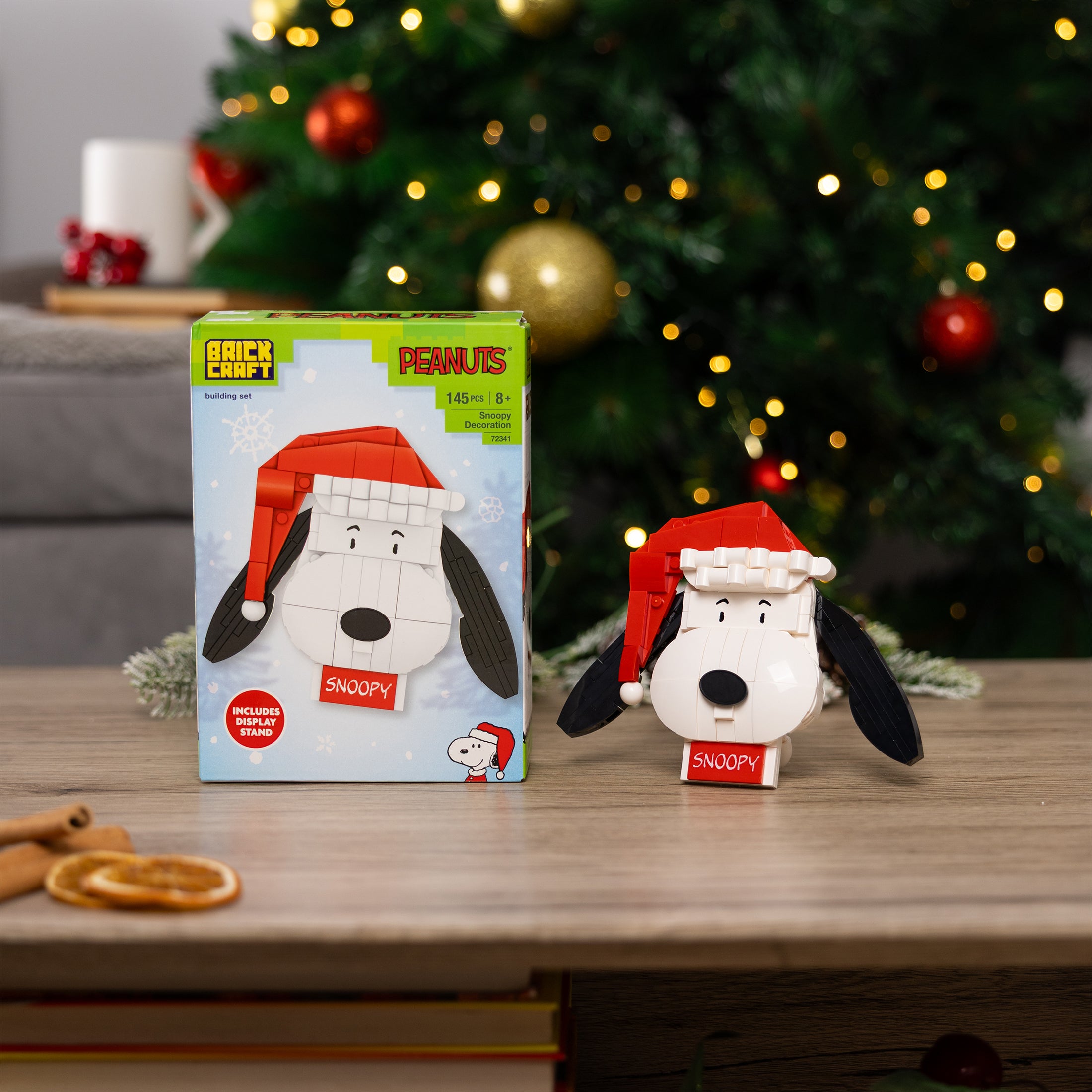 Christmas-themed Snoopy figurine with packaging on a table in front of a decorated tree.