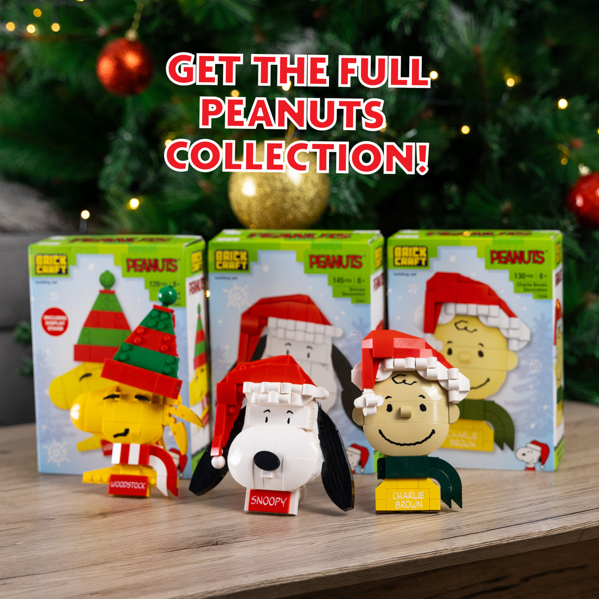 Peanuts-themed figurines with packaging on a wooden surface with a Christmas tree in the background.