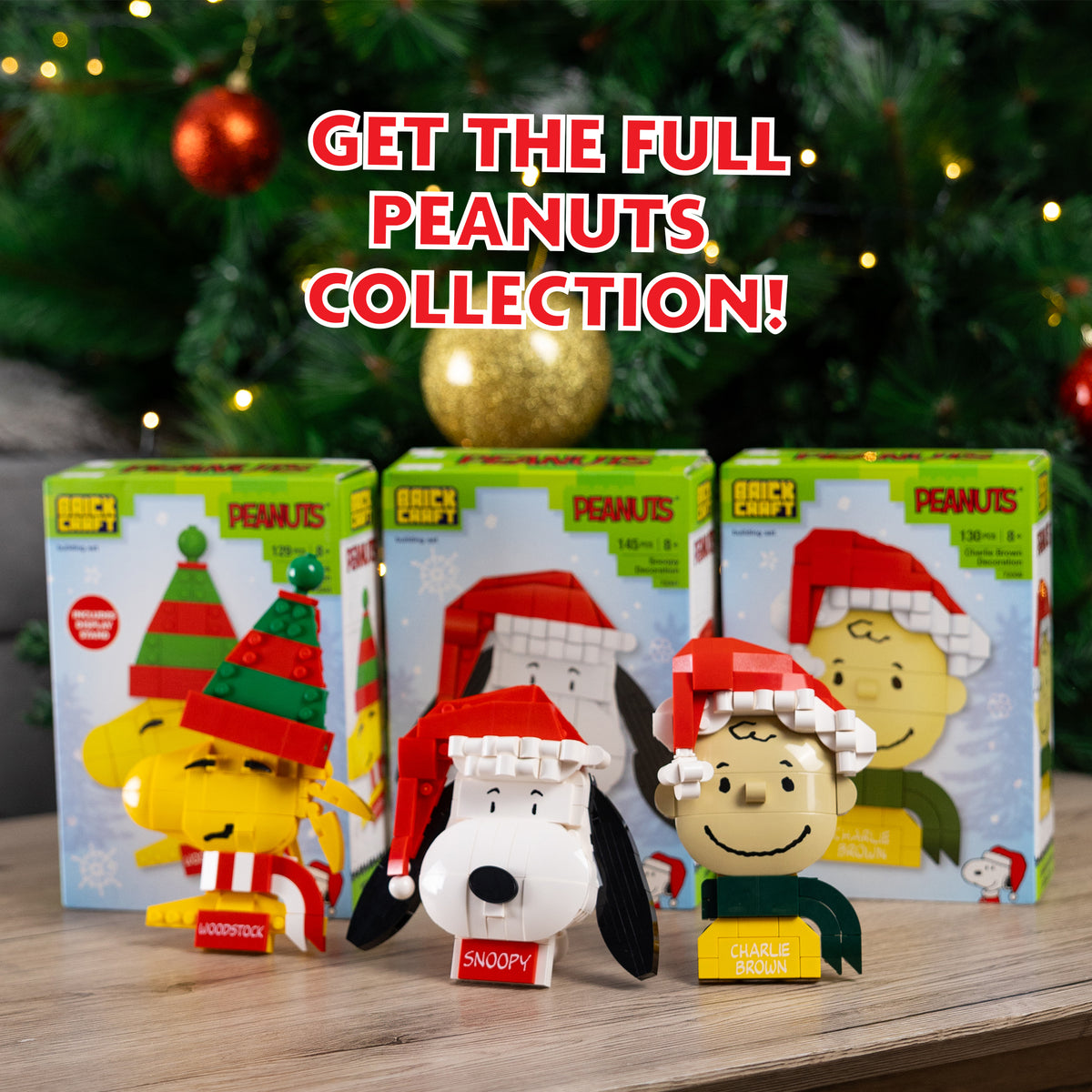 Peanuts-themed figurines with packaging on a wooden surface with Christmas tree in the background.
