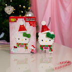 Hello Kitty Christmas ornament with packaging on a reflective surface with a blurred festive background