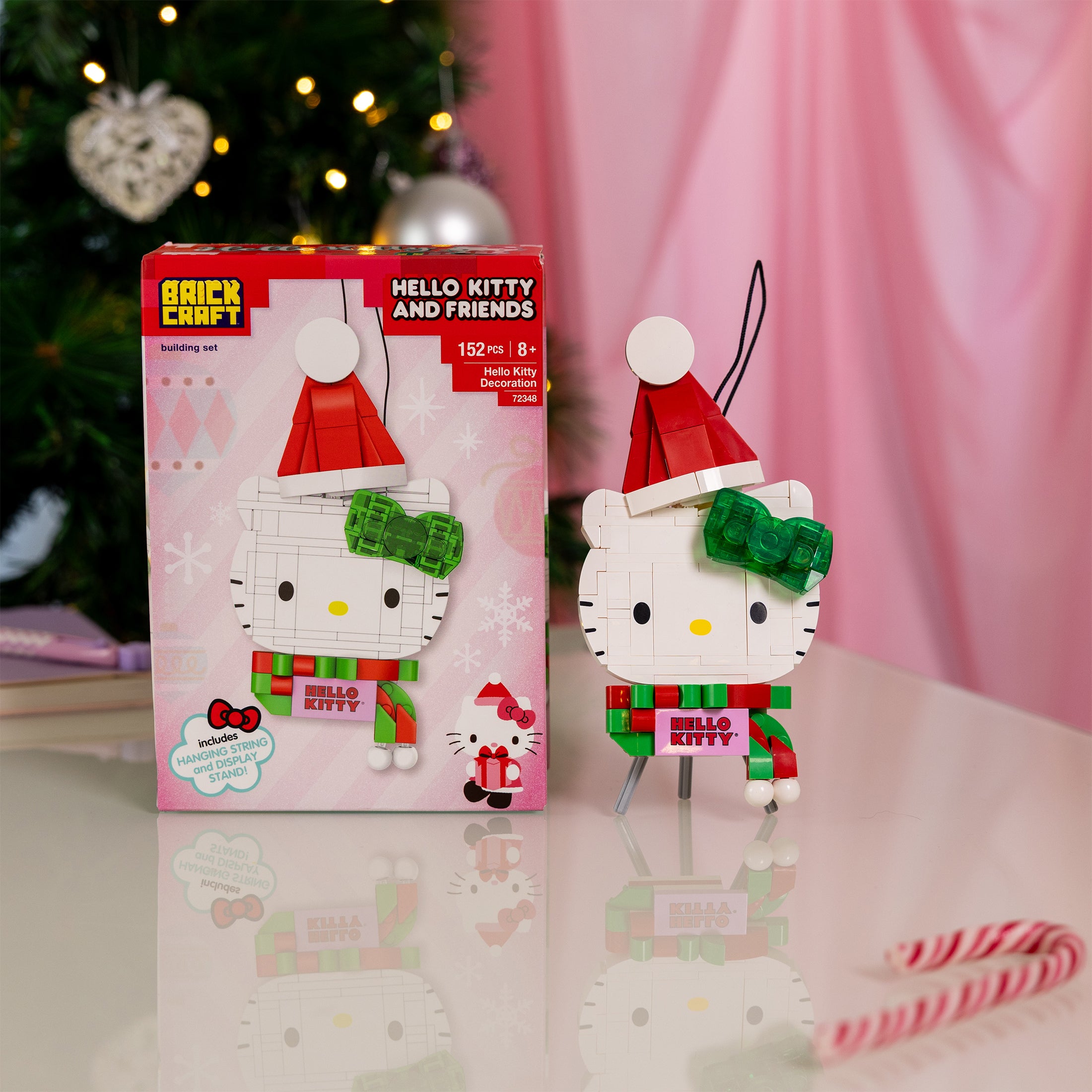 Hello Kitty Christmas ornament with packaging on a reflective surface with a blurred festive background