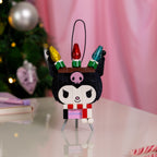 Decorative Christmas ornament with a cartoon character on a stand, blurred Christmas tree and pink curtain in the background.