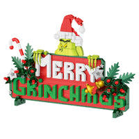 Decorative sign with 'Merry Grinchmas' text featuring a Grinch character on a white background.