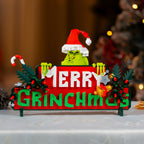 Decorative sign with Grinch-themed text and design on a blurred Christmas tree background