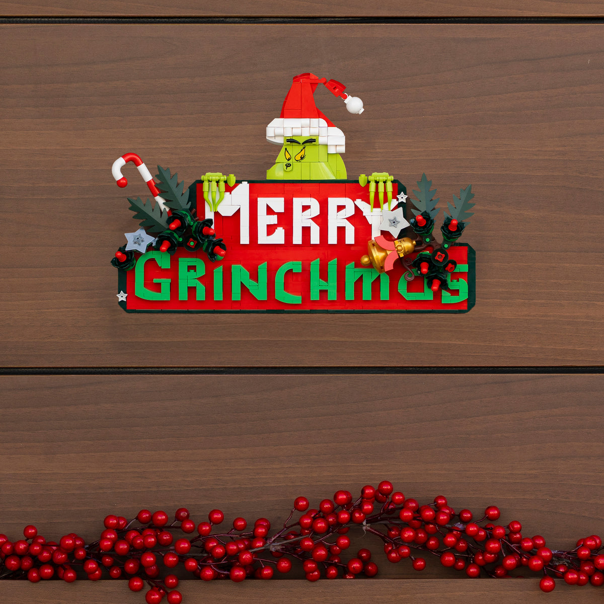 Decorative sign with Grinch face and 'Merry Grinchmas' text on a wooden background.