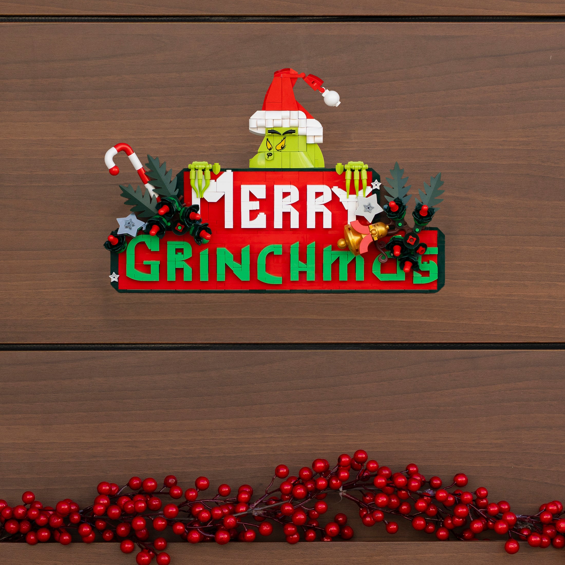 Decorative sign with Grinch face and 'Merry Grinchmas' text on a wooden background.