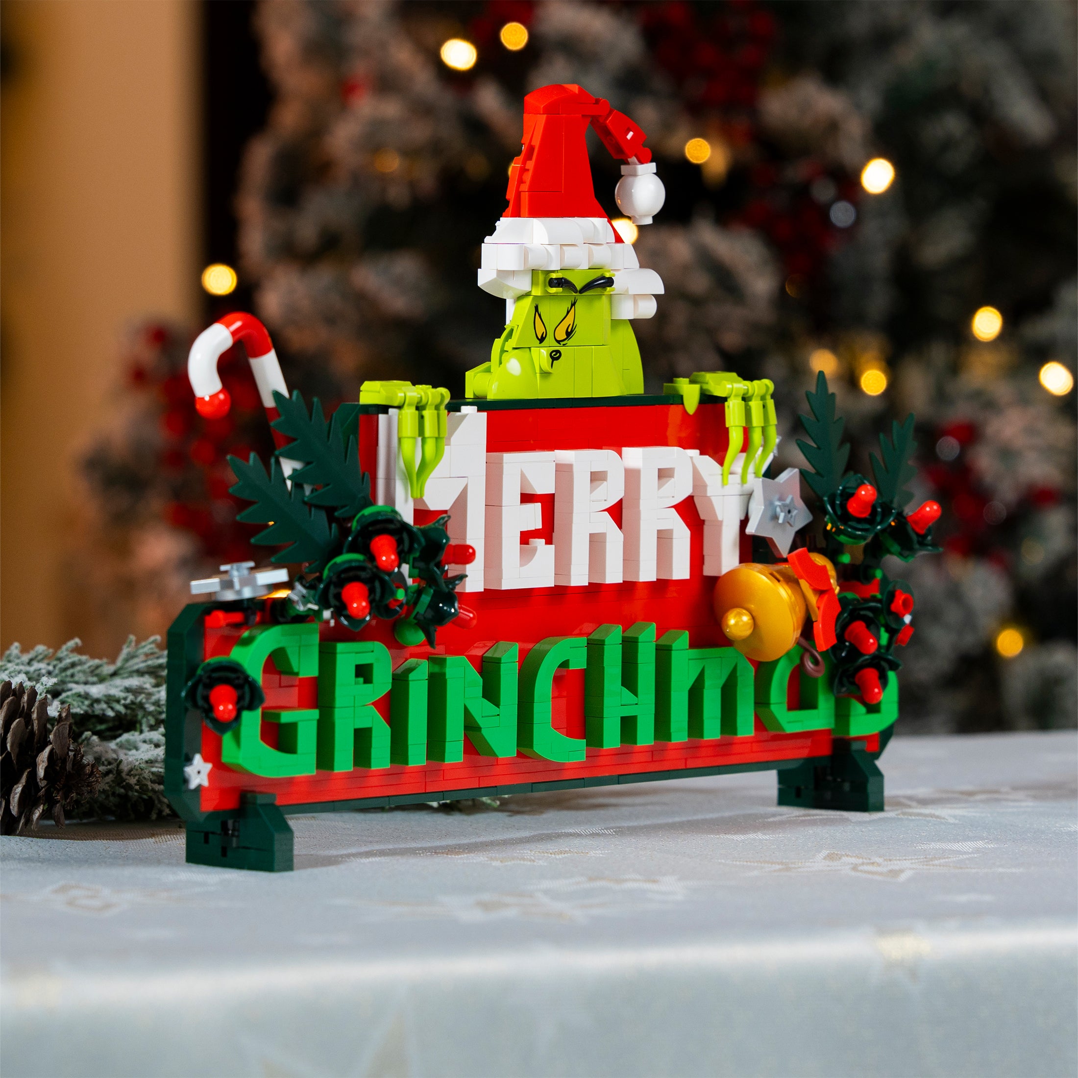 Decorative sign with a Grinch design and 'Merry Grinchmas' text, set against a blurred festive background.