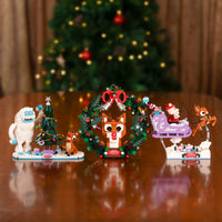 Set of Christmas-themed figurines on a wooden surface with a blurred Christmas tree in the background.