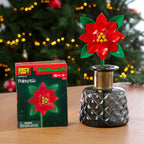 Decorative poinsettia in a vase next to its packaging in front of a Christmas tree.