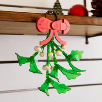 Christmas mistletoe ornament with red bow on a wooden surface