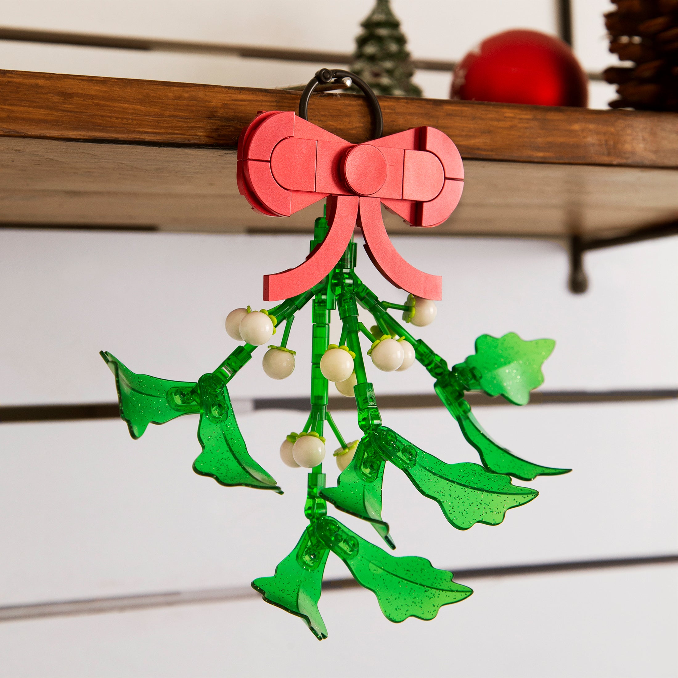 Christmas mistletoe ornament with red bow on a wooden surface