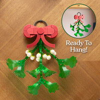 Decorative mistletoe with a red bow on a wooden surface, labeled 'Ready To Hang'.