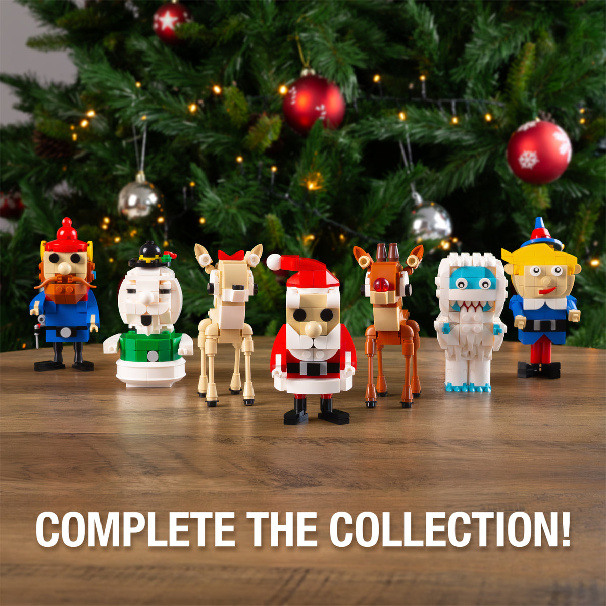 Set of Christmas-themed figurines on a wooden surface with a decorated tree in the background.